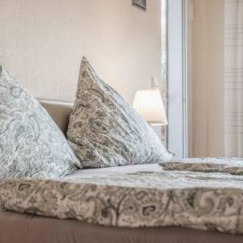 Modernes und helles Wohn-Schlafzimmer in der Park & Meer Ferienwohnung mit gemütlichem Boxspringbett und stilvoller Einrichtung.